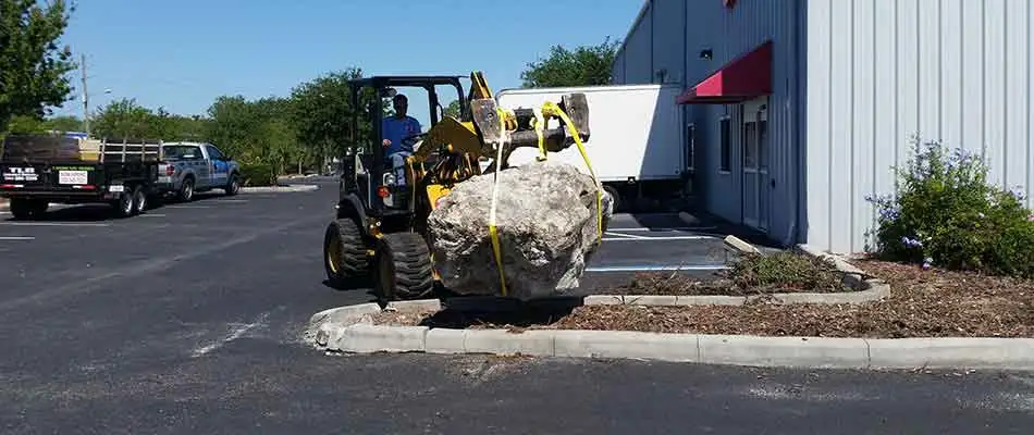 Large boulder being added during the start of a landscaping project for commercial grounds located in Brooksville.